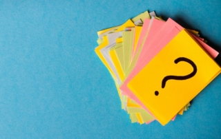 Stack of colorful paper notes, top note has a question mark